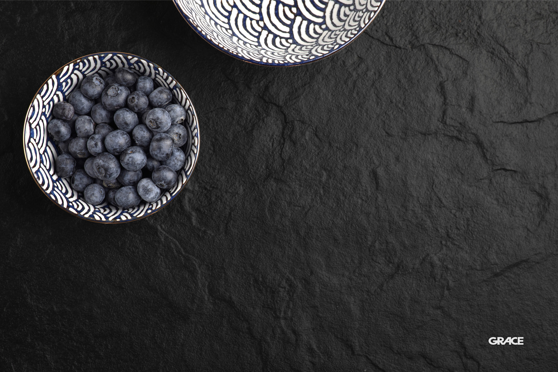 Ceramic bowl of delicious fresh blueberries on black surface